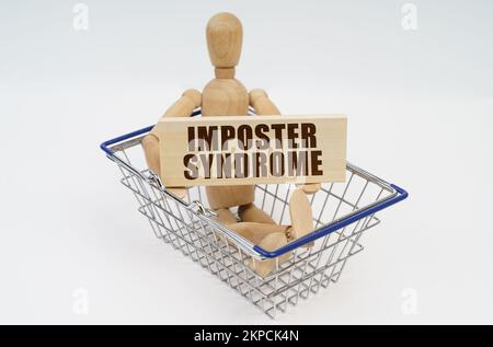 Concept commercial et financier. Un homme en bois est assis dans un panier, tenant un panneau dans ses mains - syndrome de l'affiche Banque D'Images