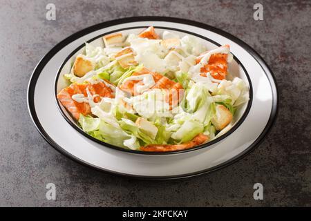 Salade césar au saumon grillé avec croûtons frais, laitue et parmesan assaisonnés de sauce délicate dans une assiette sur la table. Horizontale Banque D'Images