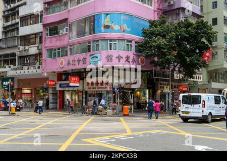 WAN Chai, Hong Kong - 29 mars 2018 : affaires dans un bâtiment rose surplombant les gens et la circulation dans la rue. Banque D'Images