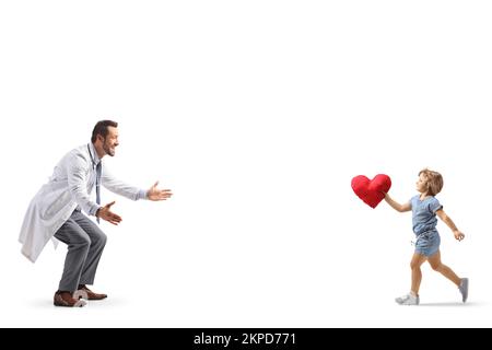 Photo de profil pleine longueur d'une petite fille qui court vers un médecin avec un coeur rouge dans ses bras isolés sur fond blanc Banque D'Images