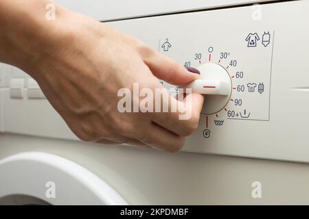 un homme choisit un mode sur un lave-linge. une personne choisit un mode de lavage à l'aide d'un interrupteur. mode de lavage. mode température. Banque D'Images