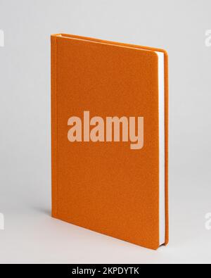 Agenda orange sur table sur fond blanc. Vue latérale Banque D'Images