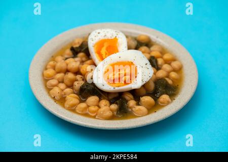 Pois chiches bouillis avec épinards et œuf bouilli sur une petite assiette Banque D'Images