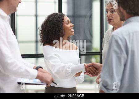 Des hommes d'affaires multiethniques souriants se mêlant au bureau Banque D'Images