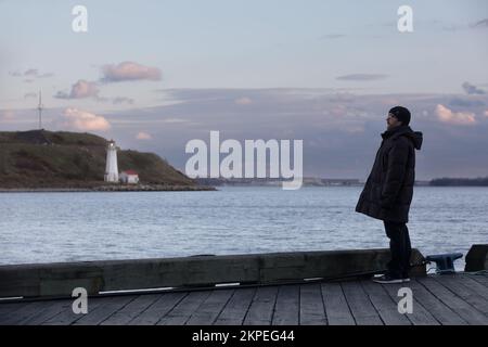 Halifax, Canada - le 19 novembre 2022 : un homme sur la rive de la baie. Phare sur l'île Georges, port de Halifax, Halifax Nouvelle-Écosse Canada Banque D'Images