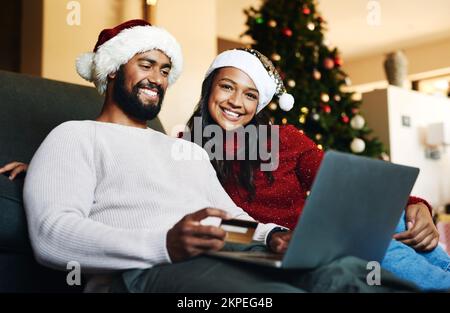 Carte de crédit, Noël et couple noir sur ordinateur portable et canapé pour les achats en ligne à la maison, facile e-commerce paiement et banque. Des gens heureux sur le canapé Banque D'Images