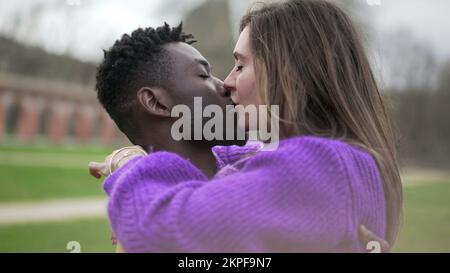 Couple Interracial heureux. Jeune femme sautant dans les bras de petit ami à park4 ans Banque D'Images