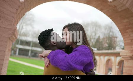 Couple Interracial heureux. Jeune femme sautant dans les bras de petit ami au parc Banque D'Images