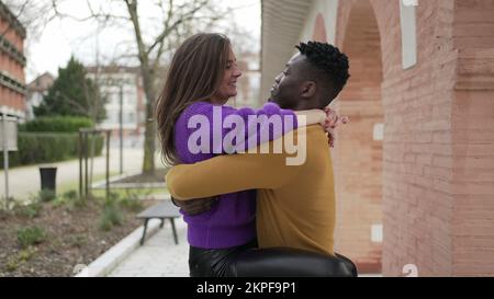 Couple Interracial heureux. Jeune femme sautant dans les bras de petit ami au parc Banque D'Images