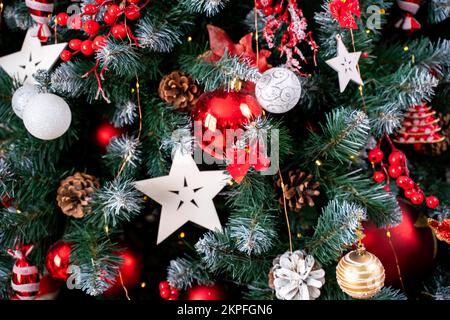 Gros plan d'un sapin de Noël à la décoration festive avec des boules sur un fond de fée étincelant et flou. Guirlande lumineuse avec effet de flou. Banque D'Images