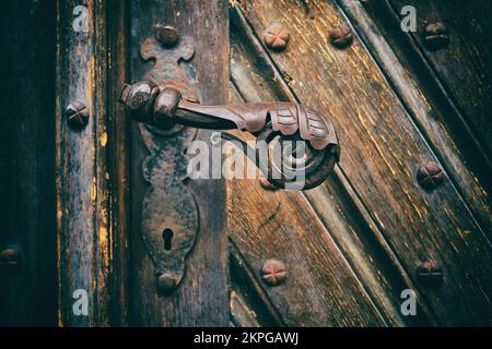 Détail d'une ancienne porte avec poignée en fer forgé et trou de serrure. Fragment d'une ancienne porte marron. Banque D'Images