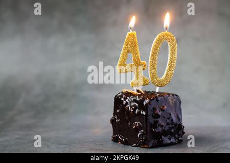 Gâteau au chocolat d'anniversaire avec le nombre quarante bougies allumées sur fond sombre avec espace de copie pour vos salutations Banque D'Images