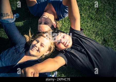 Une famille joyeuse et excitée jouant autour d'un pré d'été vert pendant apprécier le grand air Banque D'Images