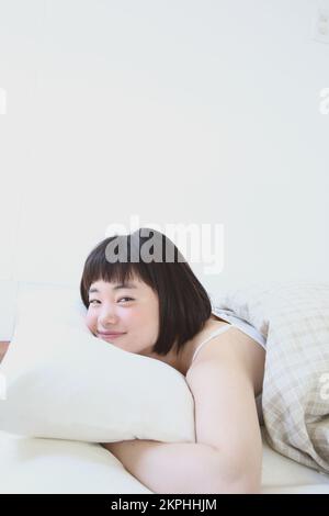 Jeune japonaise se détendant sur le lit Banque D'Images