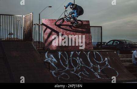 BMX Biker faire un tour de wallride dans une rampe de skatepark Banque D'Images