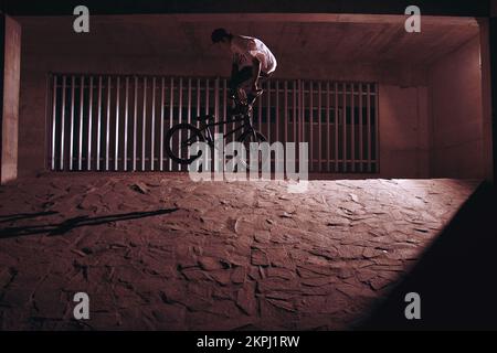 Un pilote BMX fait un whip arrière dans un mur Banque D'Images