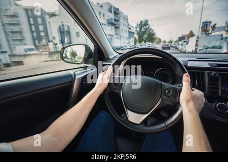 L'homme conduisant sa nouvelle voiture se trouve devant le volant, conducteur confiant dans les rues de la ville Banque D'Images