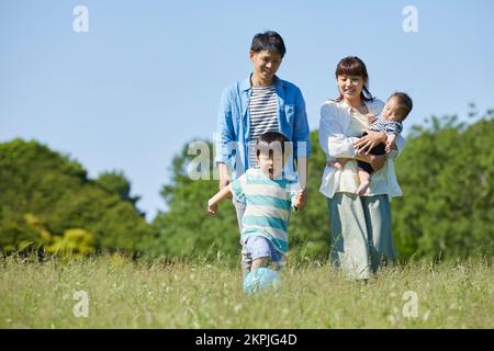 Parents japonais regardant un enfant jouer au ballon Banque D'Images