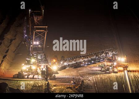 Du matériel d'exploitation minière lourd est en service dans une mine à ciel ouvert au crépuscule. Banque D'Images