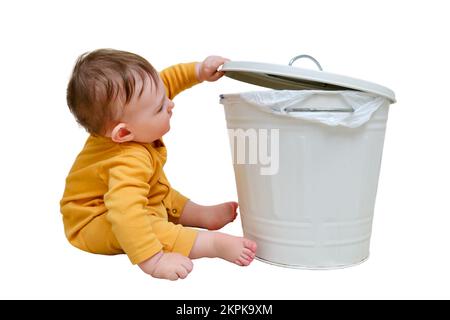 Bébé garçon ouvre une poubelle avec des déchets ménagers, isolée sur un fond blanc. Problèmes de sécurité des enfants dans la chambre d'accueil, petit enfant Banque D'Images