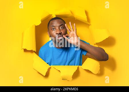 Mes lèvres sont scellées avec promesse. Un homme afro-américain sérieux garde la bouche fermée, fait un geste de fermeture éclair, restant silencieux Banque D'Images