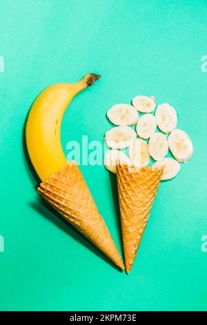 Des œuvres d'art de la crème glacée sur une composition créative de crème glacée cornets de gaufres et bananes mûres sur fond turquoise Banque D'Images