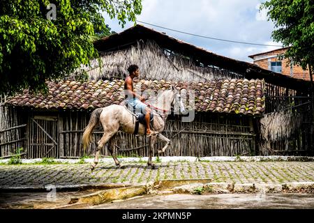 Un jeune homme à cheval passe devant une façade d'un magasin de fabrication de pots en céramique dans la ville d'Aratuipe, Ba Banque D'Images