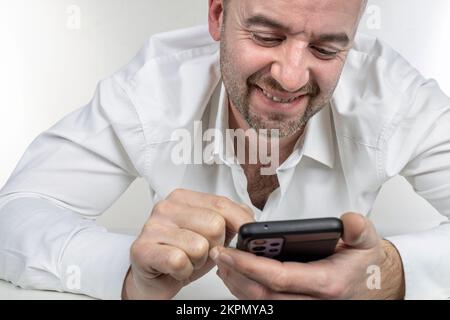 l'homme souriant utilise un smartphone Banque D'Images