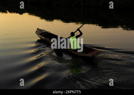 Aratuipe, Bahia, Brésil - 31 août 2018 : un pêcheur pagayant son canoë sur le fleuve Jaguaripe, ville d'Aratuipe, au coucher du soleil. Banque D'Images