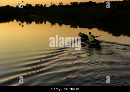 Aratuipe, Bahia, Brésil - 31 août 2018 : un pêcheur pagayant son canoë sur le fleuve Jaguaripe, ville d'Aratuipe, au coucher du soleil. Banque D'Images