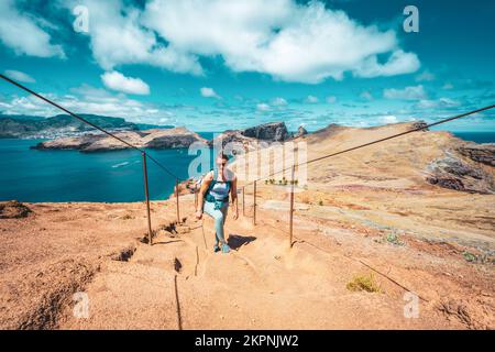 Description: Une femme athlétique monte les escaliers le long du sentier de randonnée avec vue panoramique sur l'île de Madeiran. São Lourenço, Île de Madère, Portugal, Europe. Banque D'Images