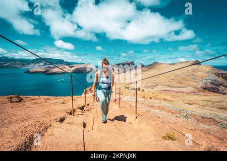 Description: Une femme athlétique monte les escaliers le long du sentier de randonnée avec vue panoramique sur l'île de Madeiran. São Lourenço, Île de Madère, Portugal, Europe. Banque D'Images