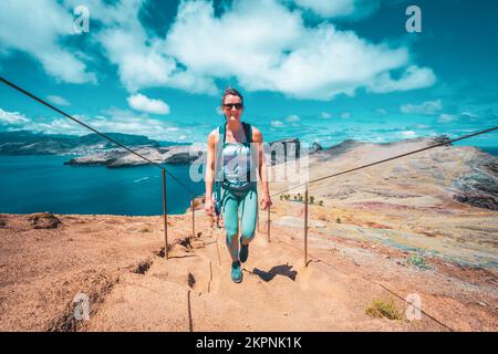 Description: Une femme athlétique monte les escaliers le long du sentier de randonnée avec vue panoramique sur l'île de Madeiran. São Lourenço, Île de Madère, Portugal, Europe. Banque D'Images