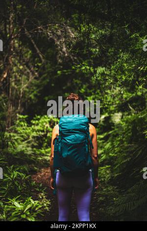 Description: Femme athlétique avec sac à dos marche à travers la jungle aventureuse chemin le long de vert surgrown chemin. Levada de Caldeirão Verde, île de Madère, Banque D'Images