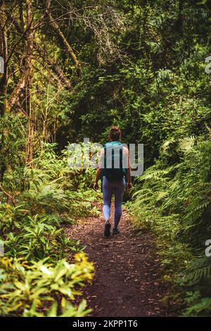 Description: Femme athlétique avec sac à dos marche à travers la jungle aventureuse chemin le long de vert surgrown chemin. Levada de Caldeirão Verde, île de Madère, Banque D'Images