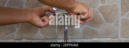 Image d'un homme qui coupe le robinet d'eau. Économiser et protéger les déchets d'eau. Bannière horizontale Banque D'Images