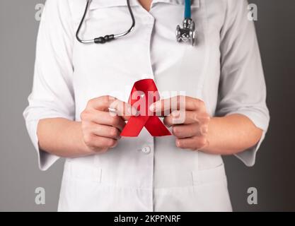 Ruban rouge dans la main des médecins, symbole de la journée de sensibilisation au VIH et au SIDA, 1 décembre soutien. Photo de haute qualité Banque D'Images