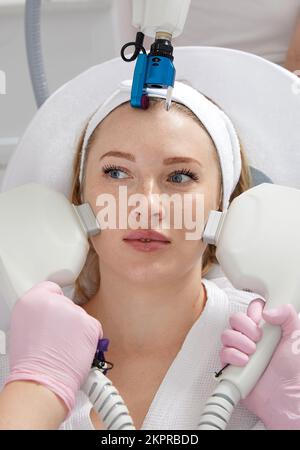 Image de cosmétologie des mains de plusieurs médecins tenant l'équipement laser sur le visage féminin. Concept de beauté et de cosmétologie Banque D'Images