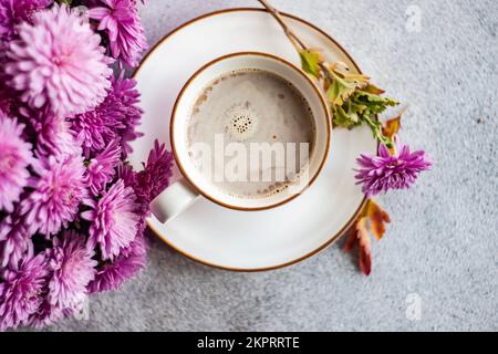 Vue en hauteur d'une tasse avec café au lait et fleurs de chrysanthème pourpres sur une table Banque D'Images