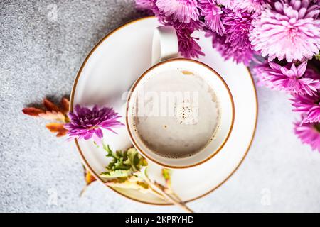 Vue en hauteur d'une tasse avec café au lait et fleurs de chrysanthème pourpres sur une table Banque D'Images