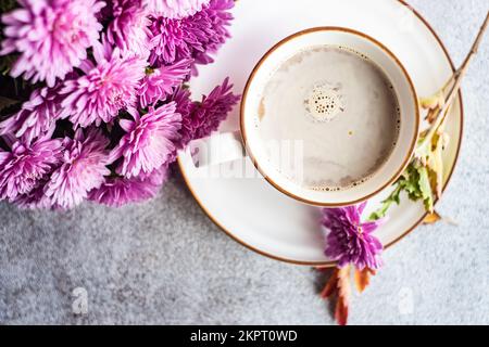 Vue en hauteur d'une tasse avec café au lait et fleurs de chrysanthème pourpres sur une table Banque D'Images