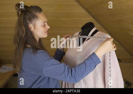 Un designer de mode prend des mesures pour un nouveau costume fait main dans un atelier. Petite entreprise. Banque D'Images