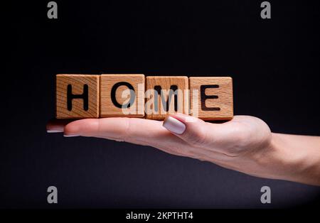 Les mains de femmes tient un cube avec des lettres, des cubes en bois avec des mots loyer vente , achat et prêt. Projet pour concepteur sur fond noir . Mots à la maison apprendre Banque D'Images