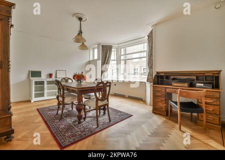 Table et chaises situées sous une lampe lumineuse près d'une plante en pot et image dans la salle à manger spacieuse de la maison Banque D'Images