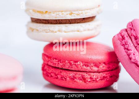 Gros plan de macarons de différentes couleurs sur fond blanc lumineux avec reflets subtils sur le plateau en marbre Dessert populaire de merengue avec des boîtes de remplissage Banque D'Images