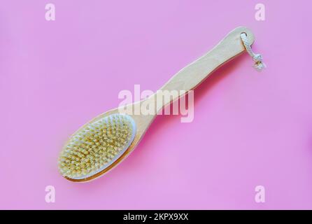 Brosse avec une poignée pour un massage anti-cellulite sec ou un brossage sur fond rose. Concept de beauté Banque D'Images