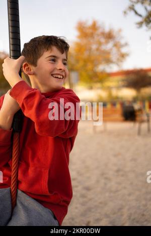 Jeune garçon jouant et s'amusant faisant des activités à l'extérieur. Le bonheur et le concept d'enfance heureuse. Balançoire enfant sur corde Banque D'Images