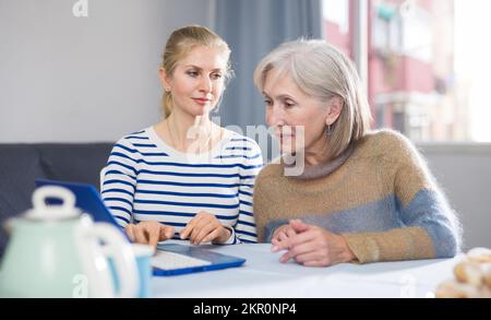 Mère et fille adulte regardant l'écran d'ordinateur portable à la maison Banque D'Images