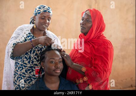 Un militaire américain obtient ses cheveux tressés par des femmes locales d'Agadez, au Niger, sur un marché de femmes vendeurs à la base aérienne 201, au Niger, le 5 novembre 2022. L'événement, avec le soutien des forces armées (FAN) du Nigerien (Français : Forces armées nigériennes), coordonnées par des aviateurs du groupe expéditionnaire aérien 409th et des soldats du 443rd Bataillon des affaires civiles, ont permis à 31 vendeurs locaux d'Agadez de vendre leurs marchandises aux membres du service AB 201 dans un lieu centralisé. Le produit du marché aidera les femmes à devenir plus stables financièrement, leur permettant ainsi de f Banque D'Images