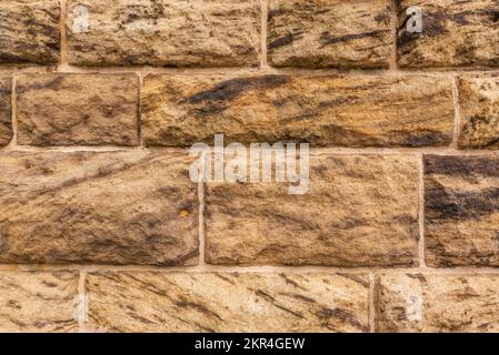 Texture d'arrière-plan d'un mur géométrique en pierre, composé de blocs de grès grossièrement sculptés Banque D'Images